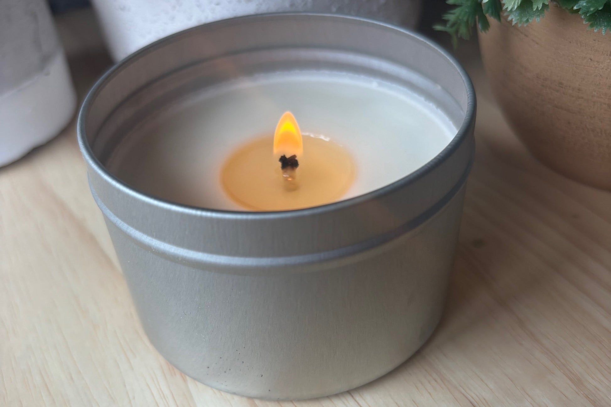 soy Candle in a metal container with the wick lit labeled volcano of sunshine