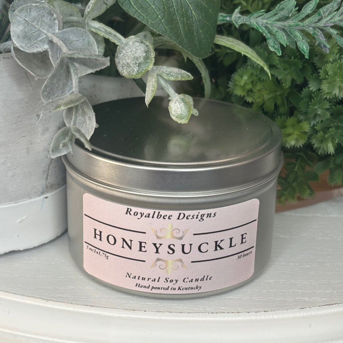 Honeysuckle candle in a tin with a pink label sold by Royalbee Designs